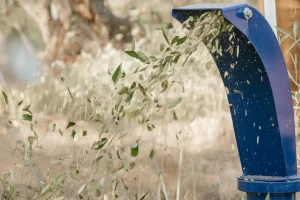 Chaff being expelled forcefully from a blue chute, showing scattered leaves and particles.