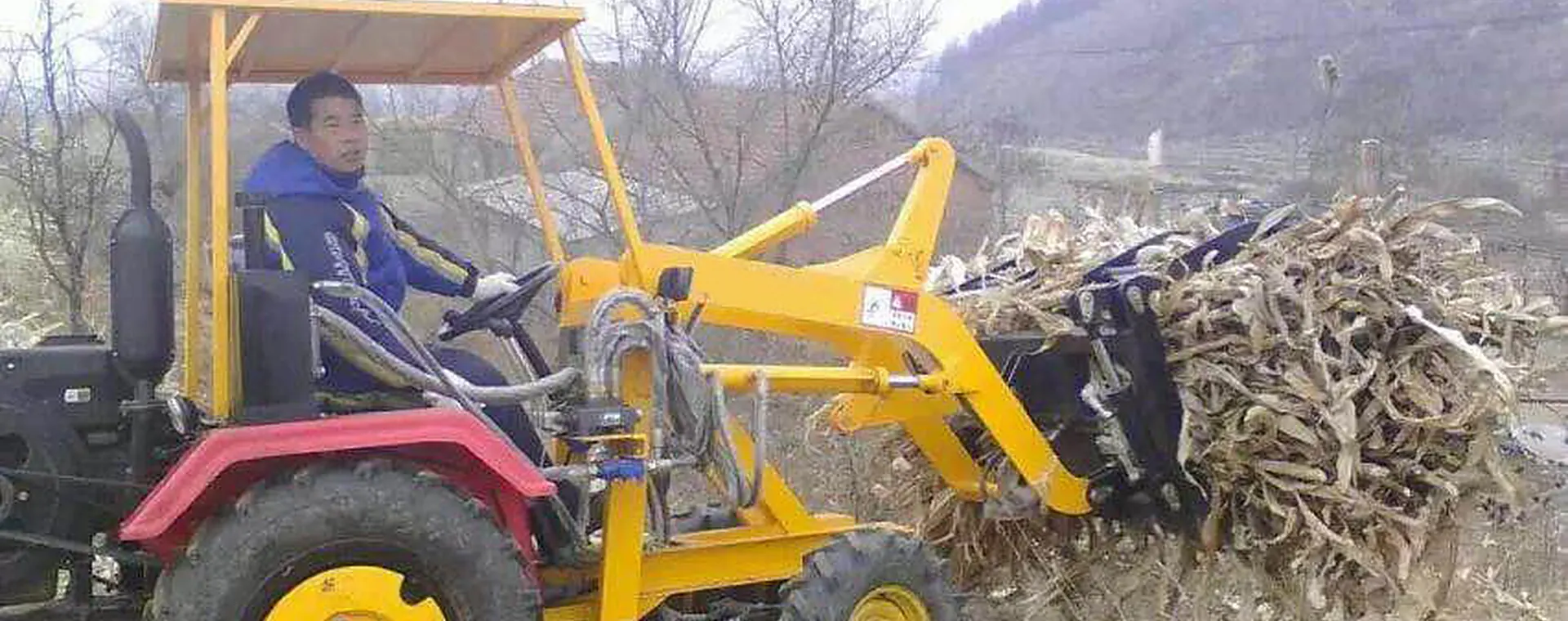 Golden Machinery GC-06 grass loader gripping a load of dry corn stalks with its hydraulic grapple in the field