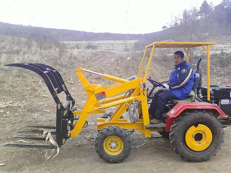 Operator driving the GC-06 grass loader with grapple across a harvested field