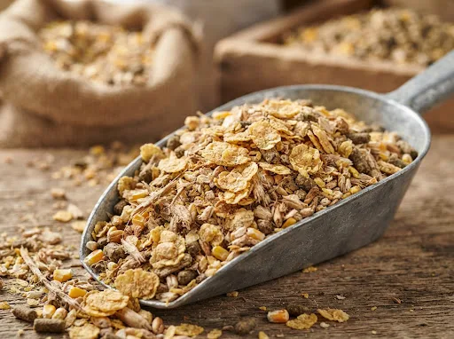 Soybean meal flakes for secondary size reduction before feed mixing